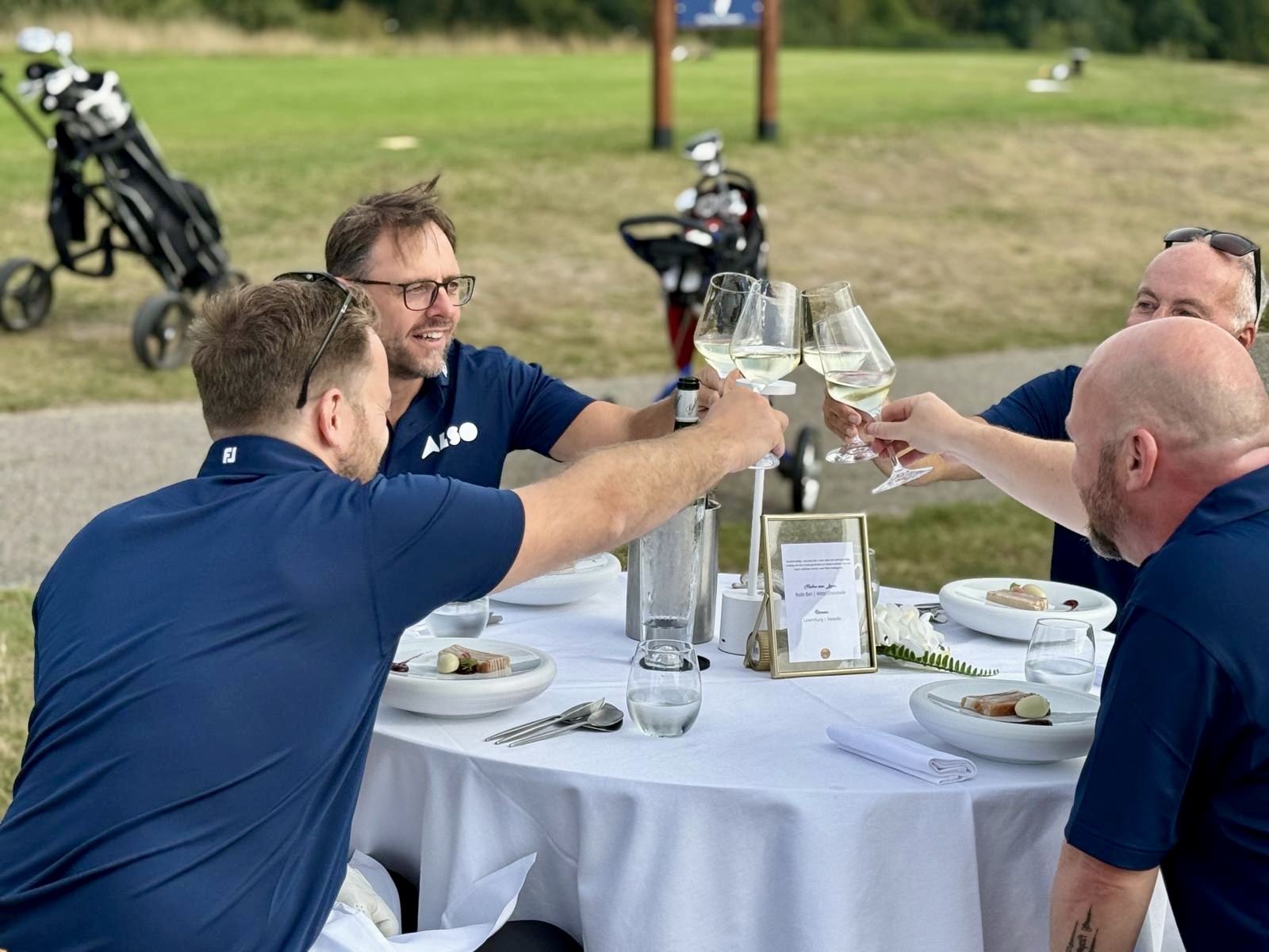 ALSO team proost aan tafel op de golfbaan