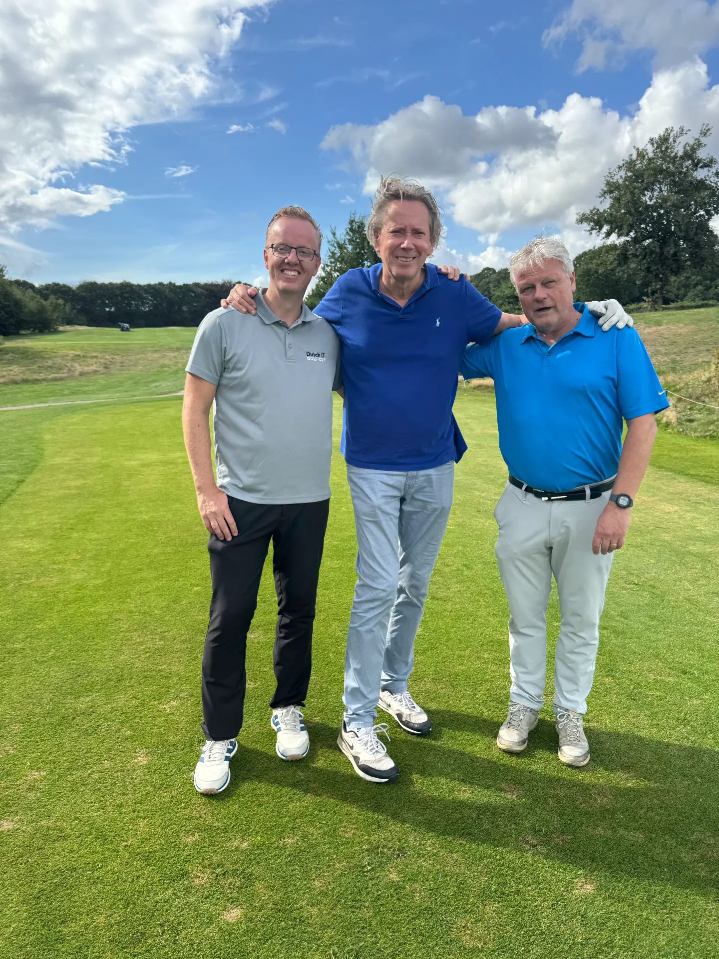 Drie deelnemers arm in arm op de fairway