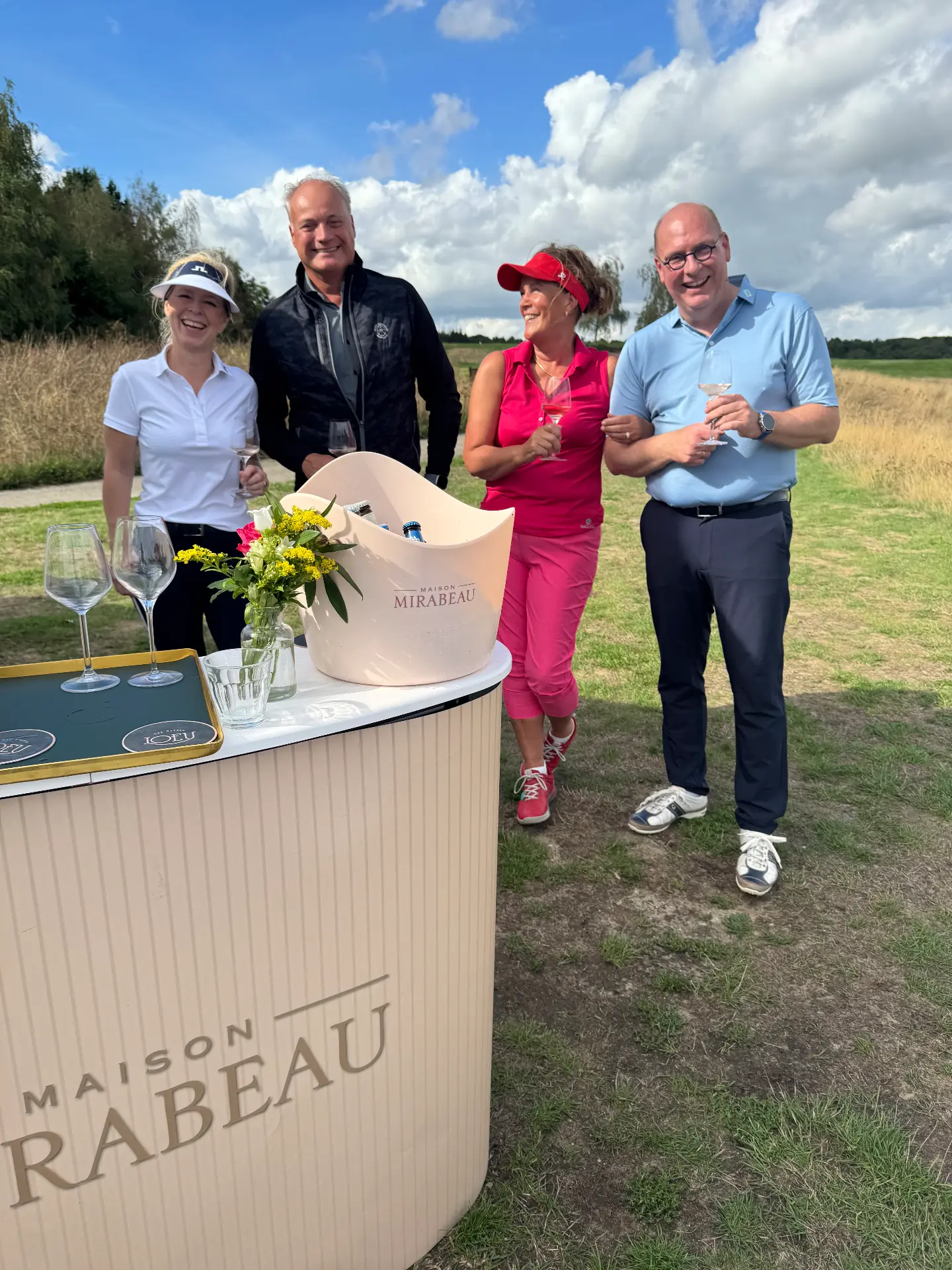 Lachende deelnemers met een glas wijn bij de wijnbar