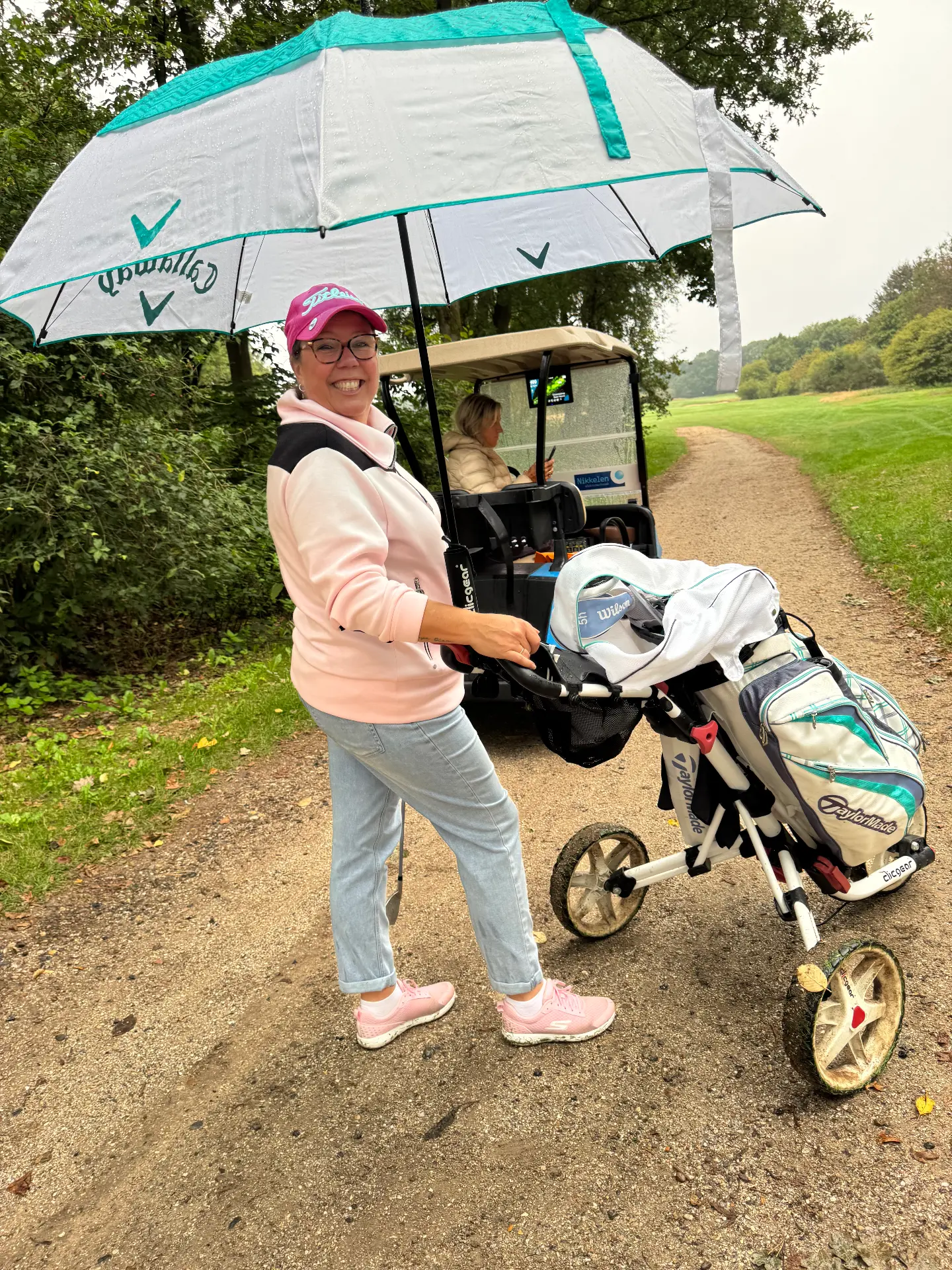 Deelneemster met paraplu en golftrolley