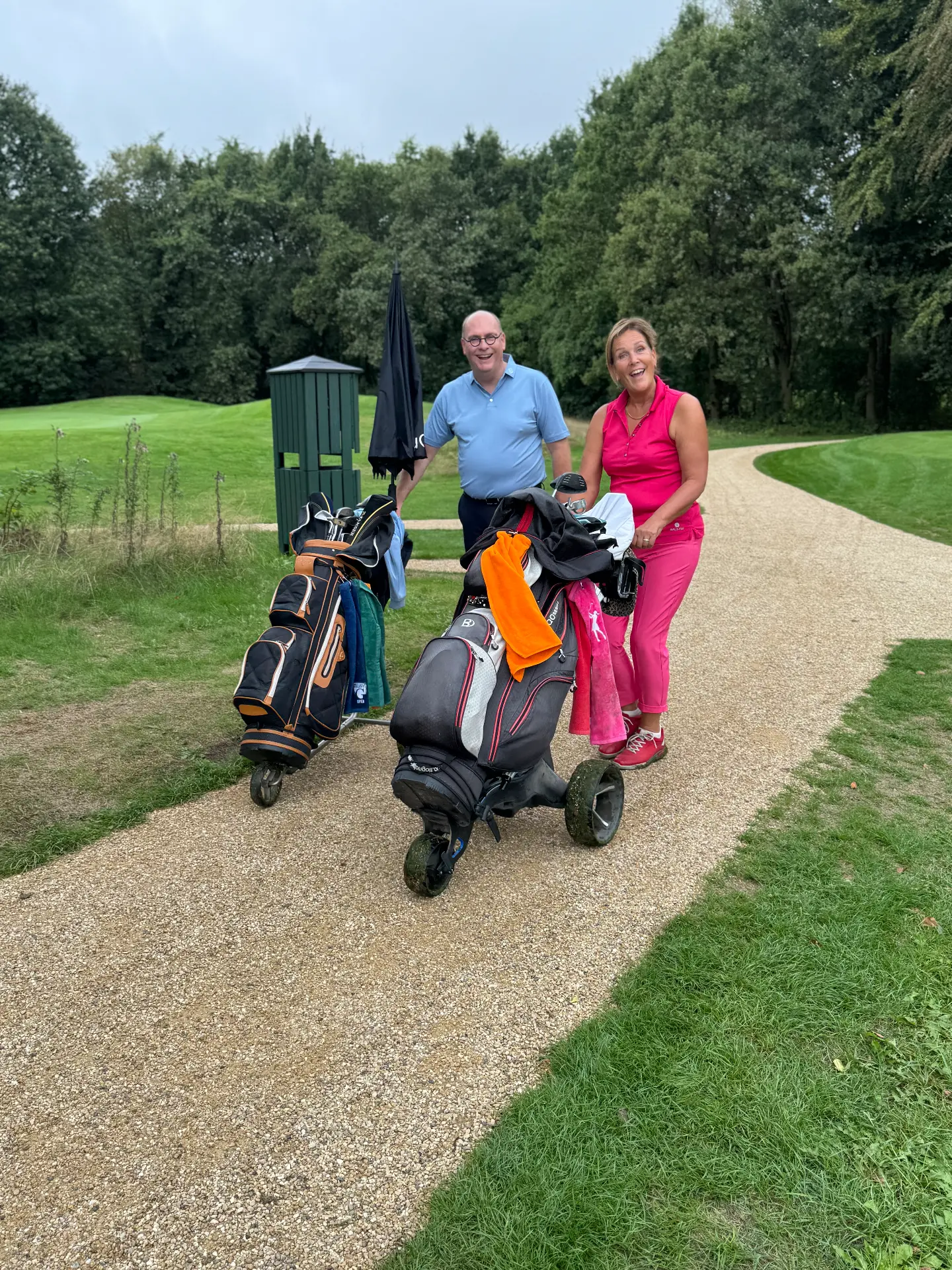 Twee deelnemers lachend met hun trolleys op het pad