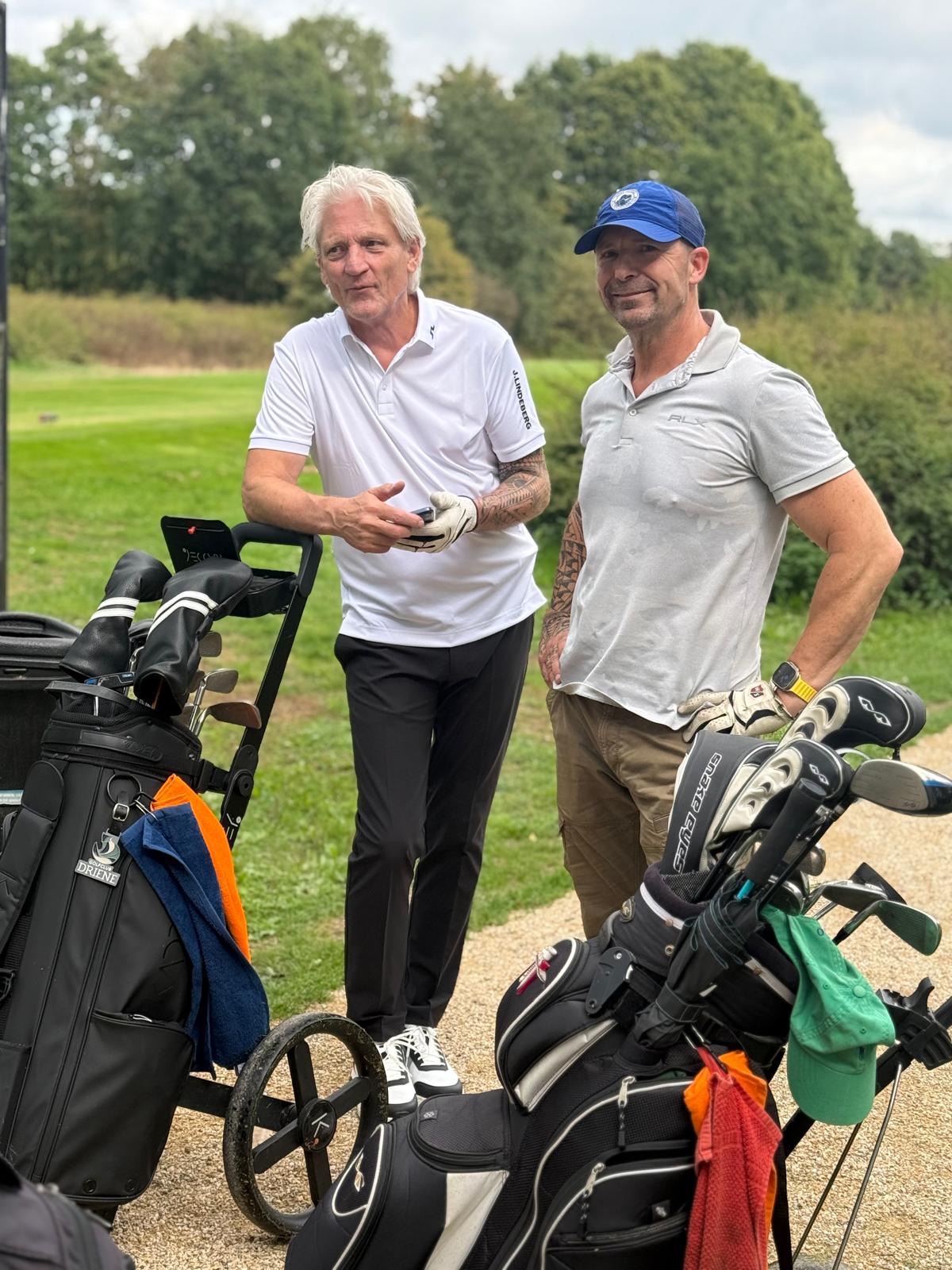 Twee deelnemers met golftrolleys op het pad